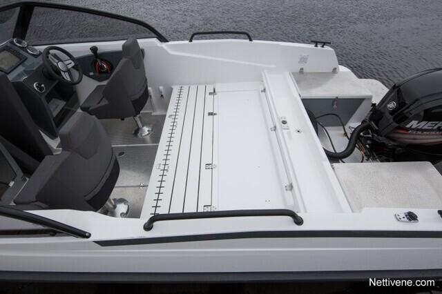 Modern boat interior featuring gray seating, control panel, and storage space, with a black outboard motor visible.